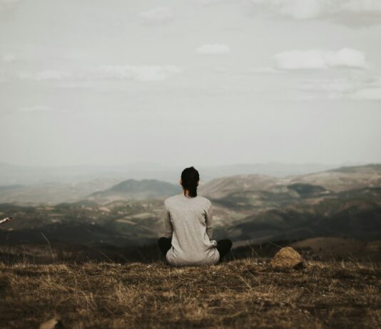 “만성피로, 단순한 피곤함이 아니다…AI 수면관리·‘마인드풀니스’로 해법 찾는다” woman sitting on cliff overlooking mountains during daytime