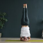 역립 요가: 세상을 거꾸로 보는 용기, 머리 서기 도전 Woman performing a headstand yoga pose indoors.