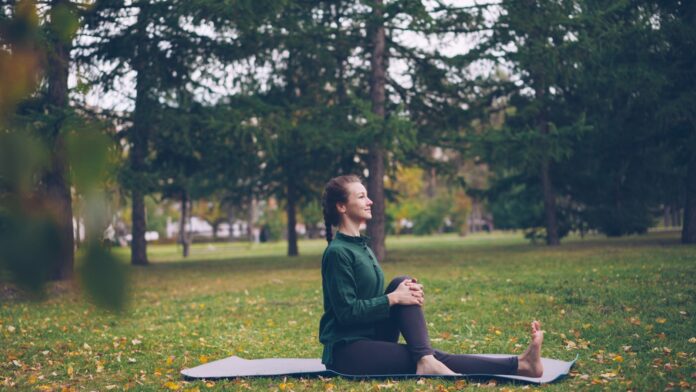 Woman practicing yoga on mat in park